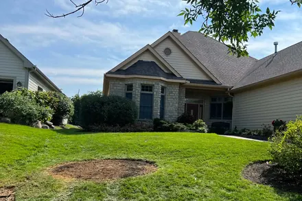 A front lawn with a circle of fresh soil where the tree and its stump used to be.