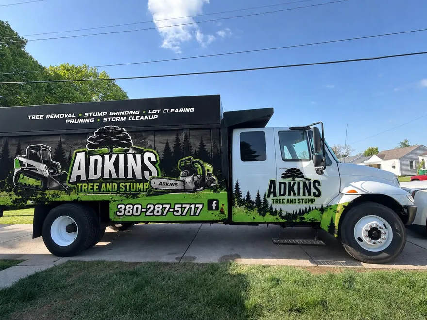 The wrapped Adkins Tree and Stump truck — tree removal, stump grinding, lot clearing, pruning and storm cleanup listed along the box.